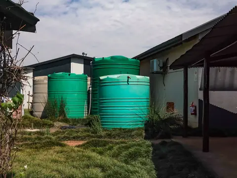 Green water storage tanks beside farm buildings