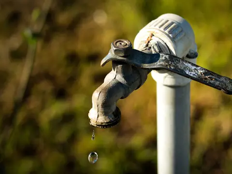 An outdoor tap with only a drip of water