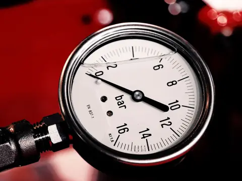 A pressure gauge on a water line, its needle near ten