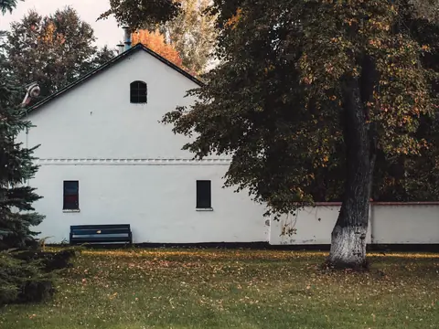 A white farmhouse under large trees