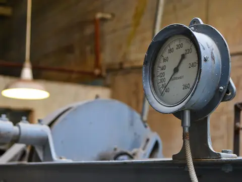 An old pressure gauge on a pipe in a workshop