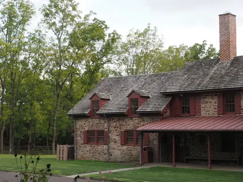 A brick farmhouse in a green yard among trees