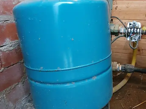 A blue well pressure tank with its pressure switch on the water line