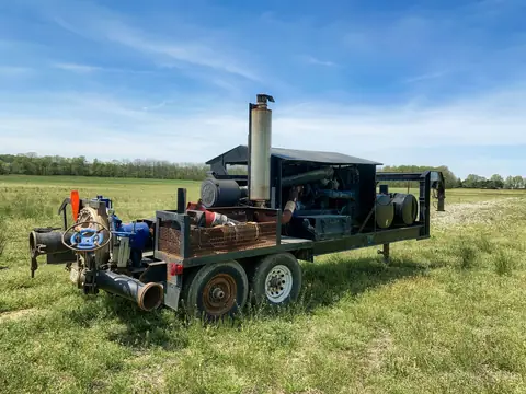 A water pump on a trailer in a green field