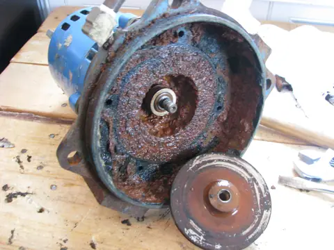 A worn water pump opened up beside its impeller on a workbench